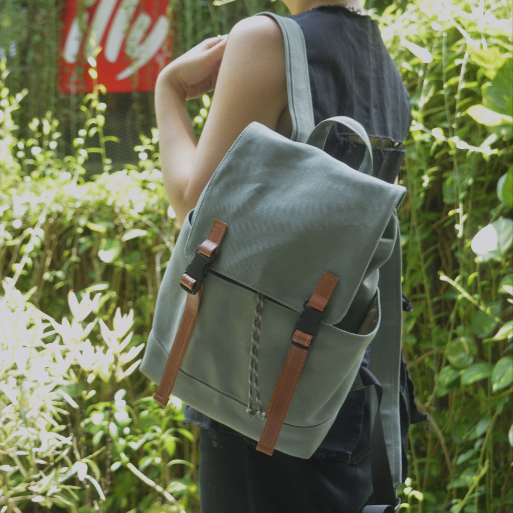 Woman carrying small green backpack on one shoulder outdoors.