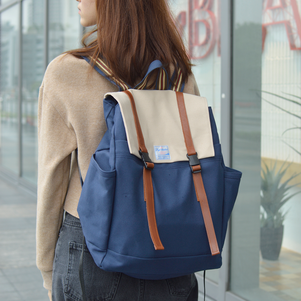 Woman wearing a blue backpack with beige accents in an urban setting