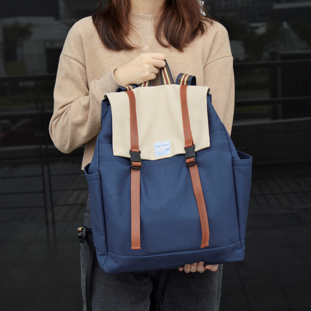 Person holding a blue and beige backpack with brown stripes.