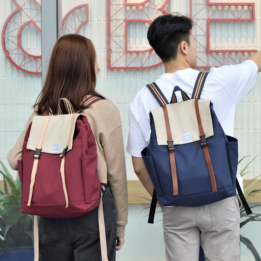 Two people wearing backpacks with a decorative wall in the background