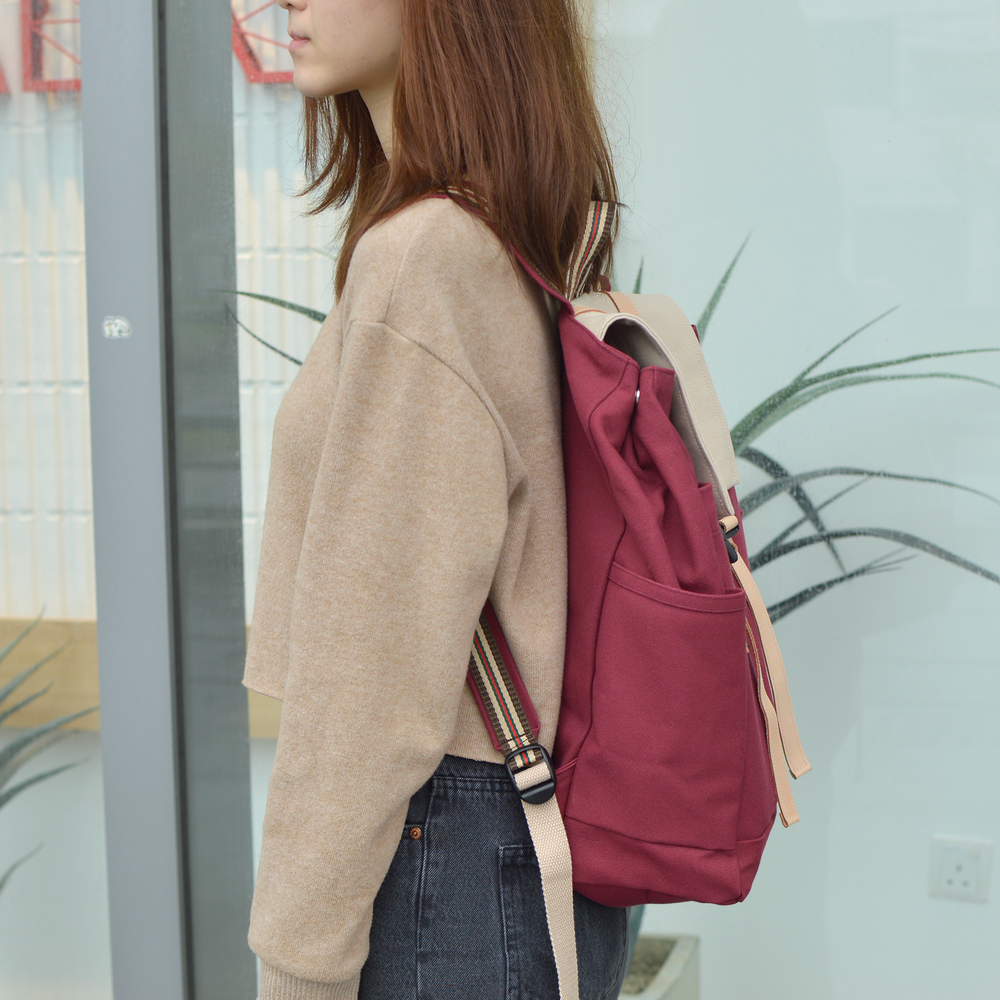 Person wearing a beige sweater and red backpack indoors