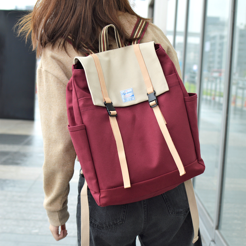 Person wearing a red and beige backpack outdoors.
