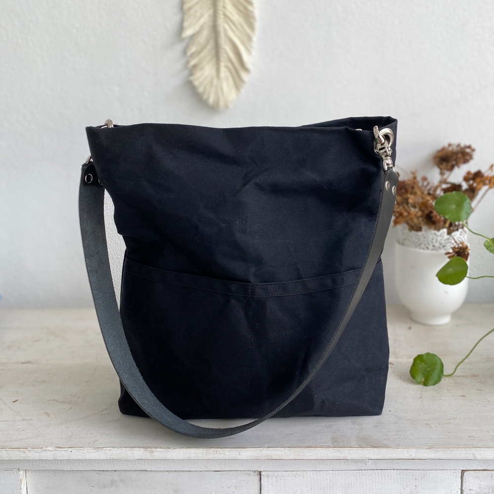 Black shoulder bag on a wooden surface with a neutral background