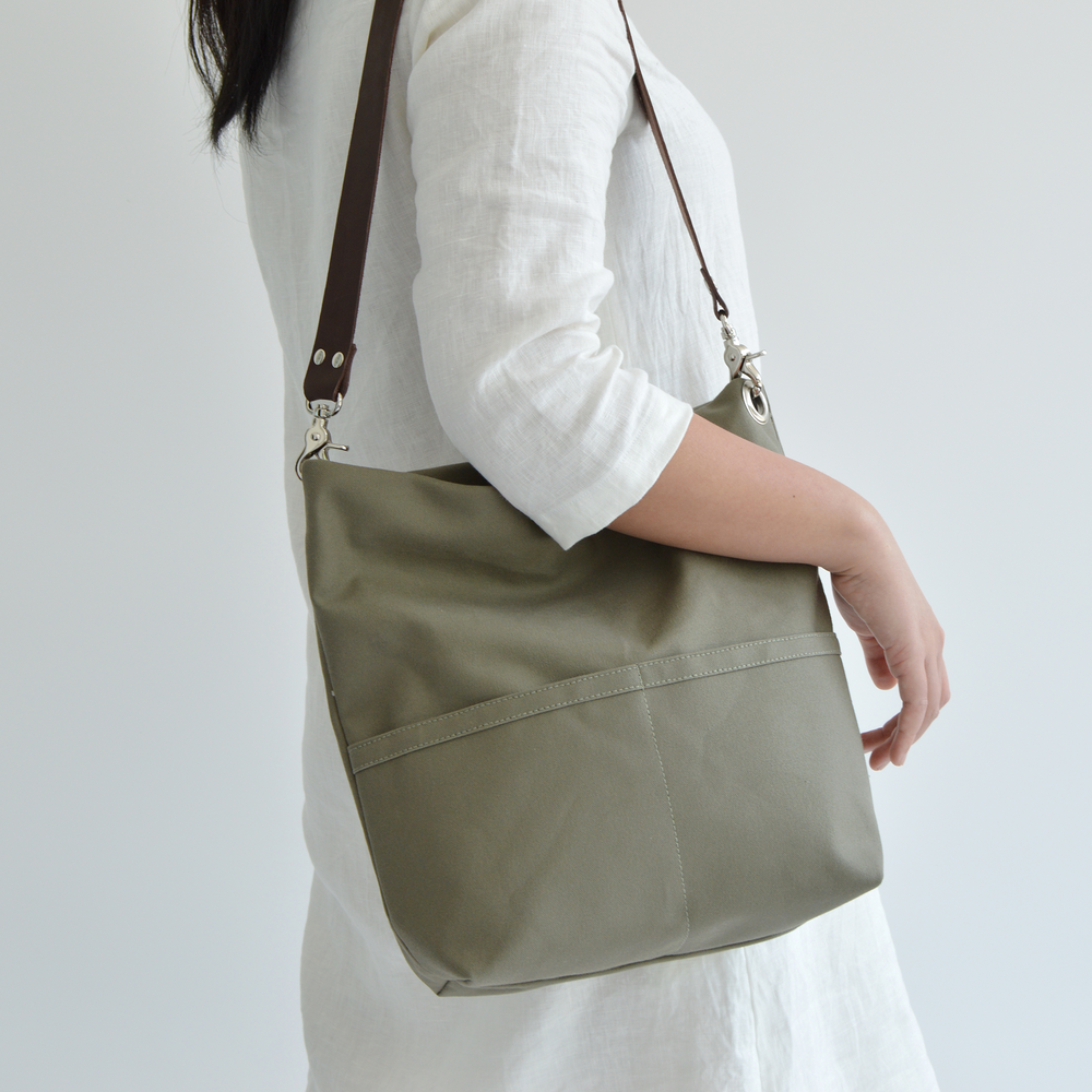 Person wearing a light green shoulder bag on a plain background