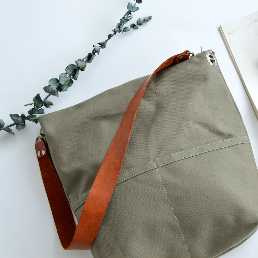 Green bag with a brown strap on a white background