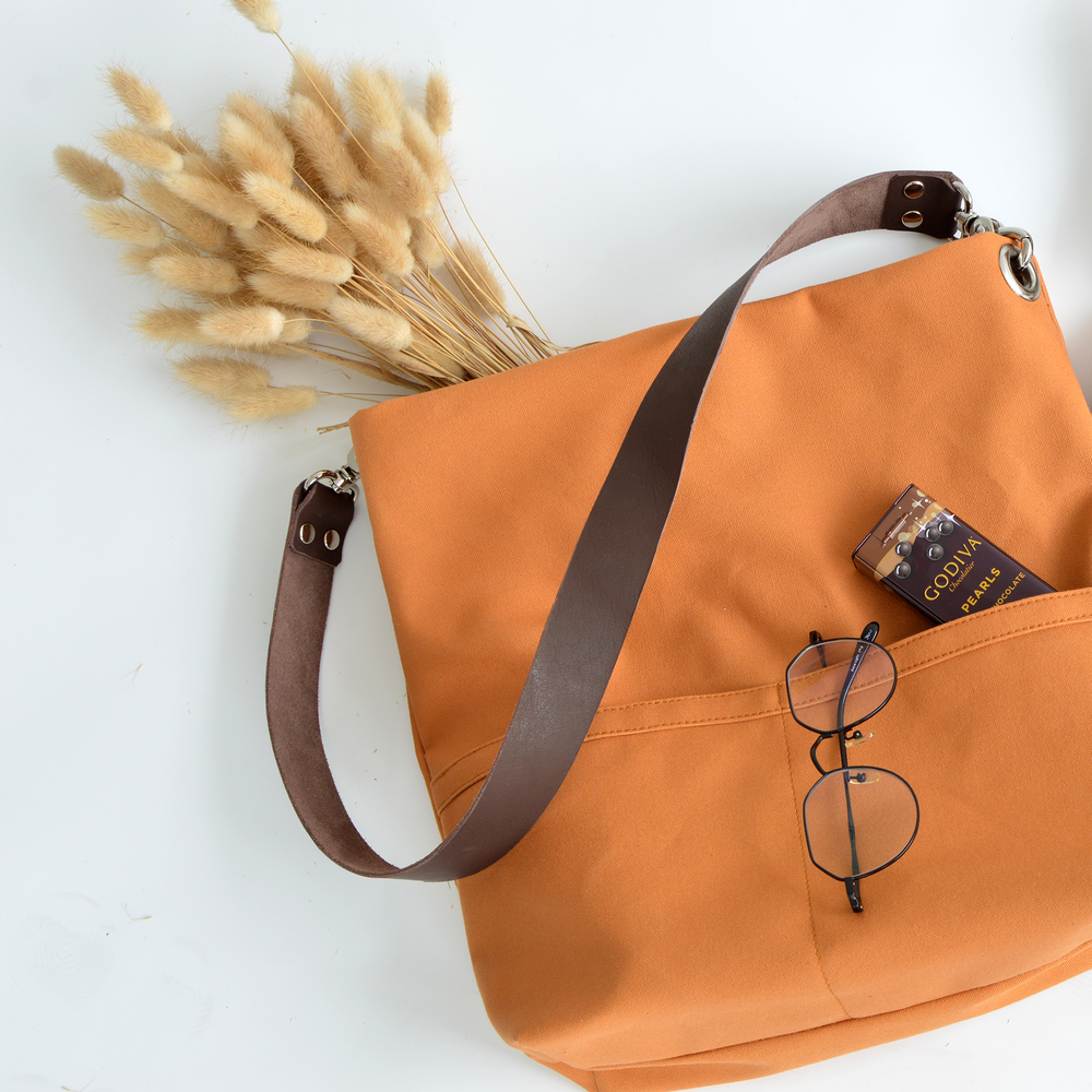 Orange bag with a brown strap and a book on a white background