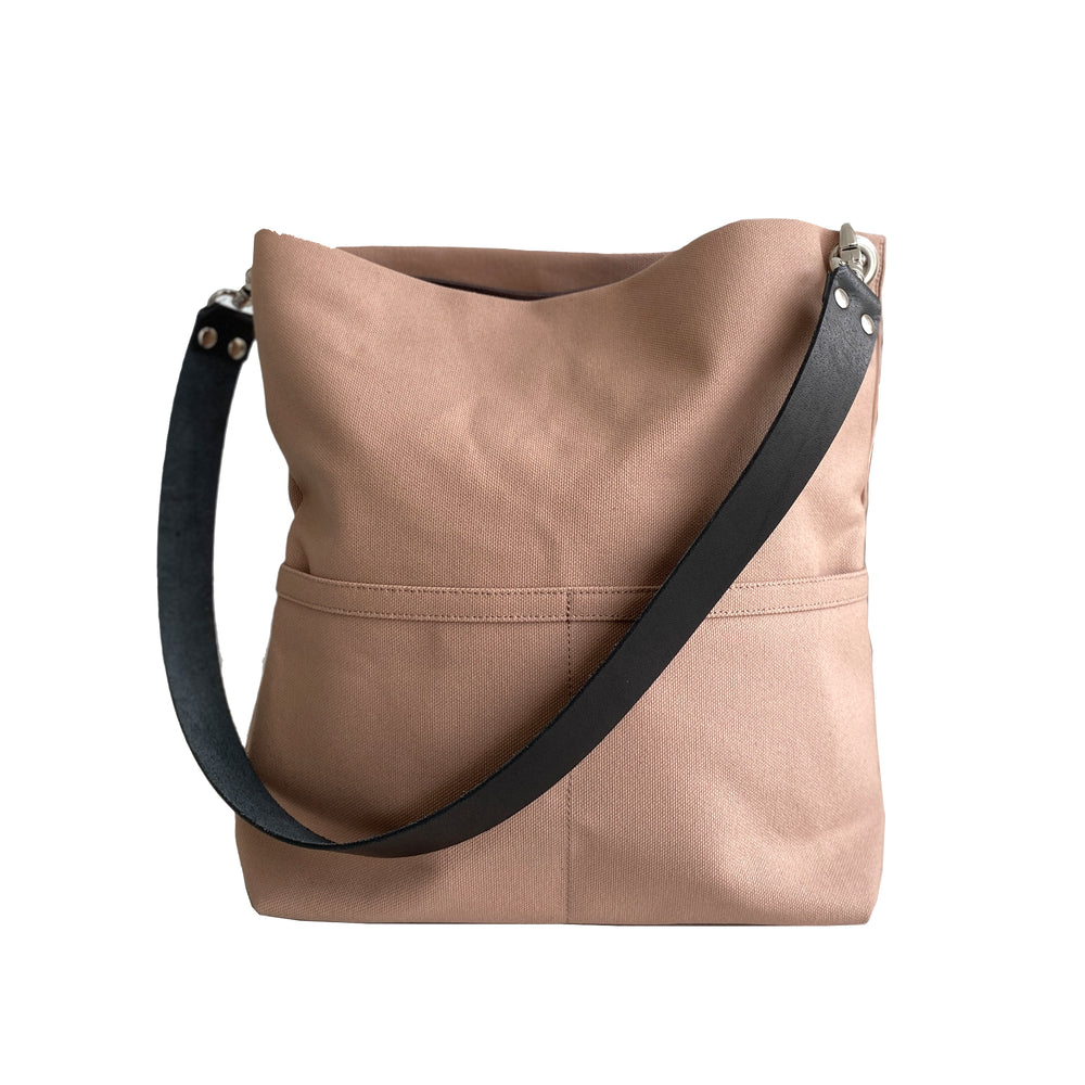 Light brown shoulder bag with black leather straps on white background.