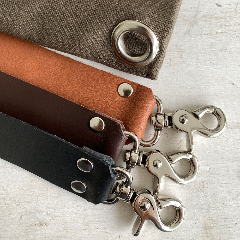 Close-up of leather straps with metal hooks on a textured surface