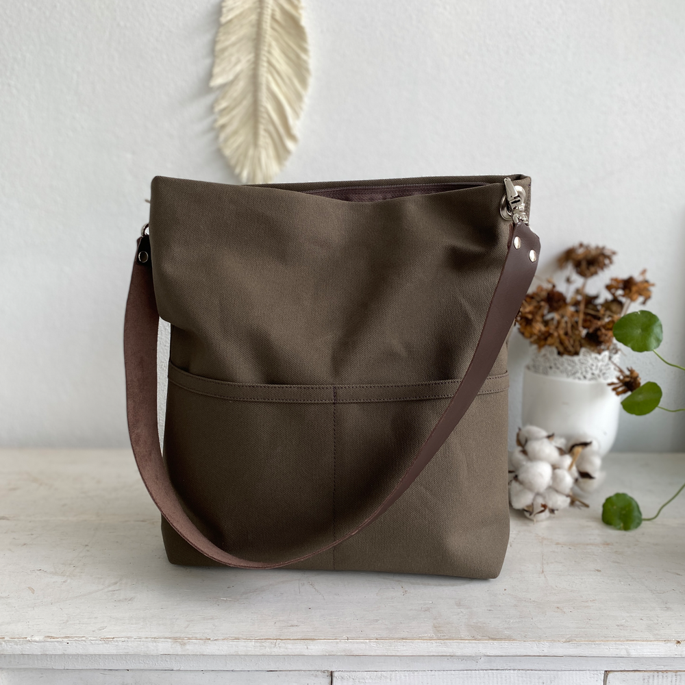 Brown tote bag on a light wooden surface with decorative elements in the background