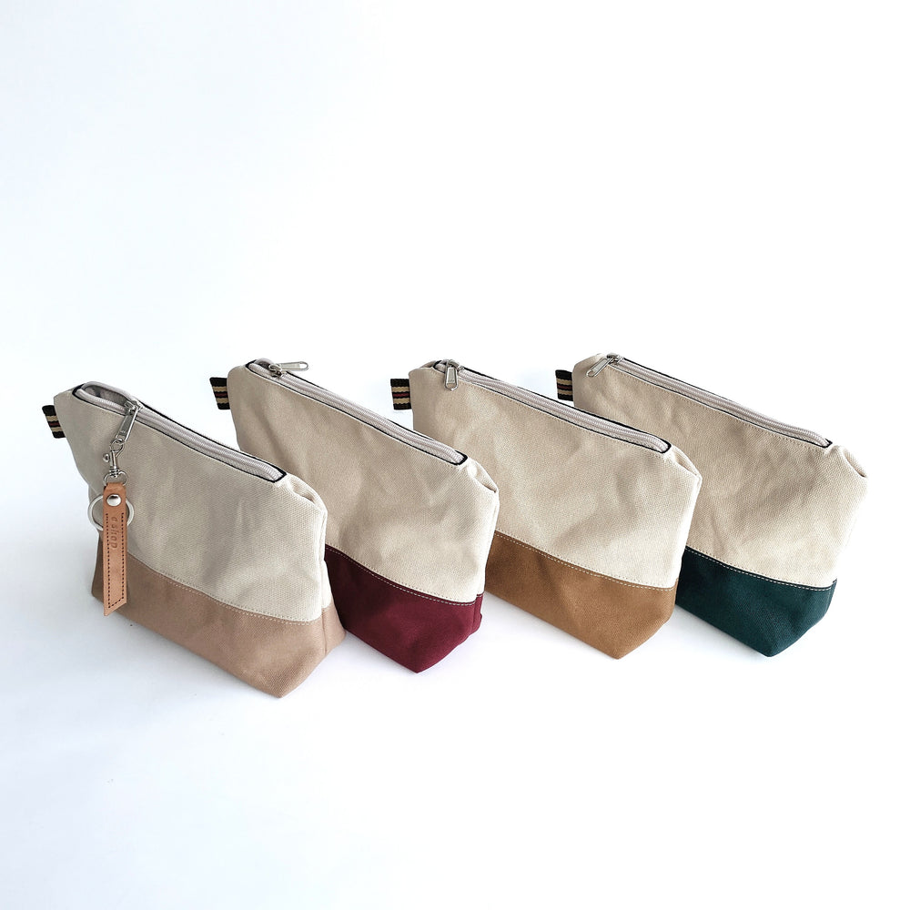 Four canvas pouches with color-blocked designs on a white background