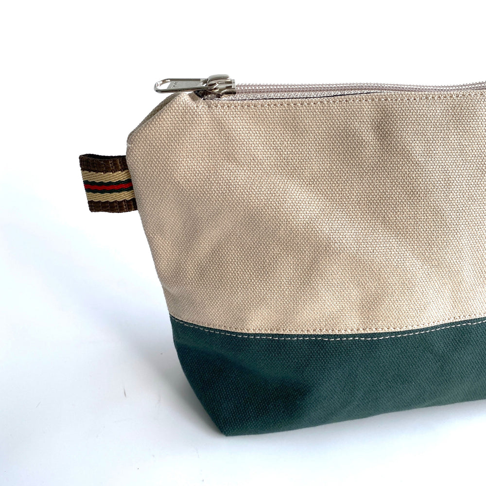 Close up of beige and green zipper pouch on a white background