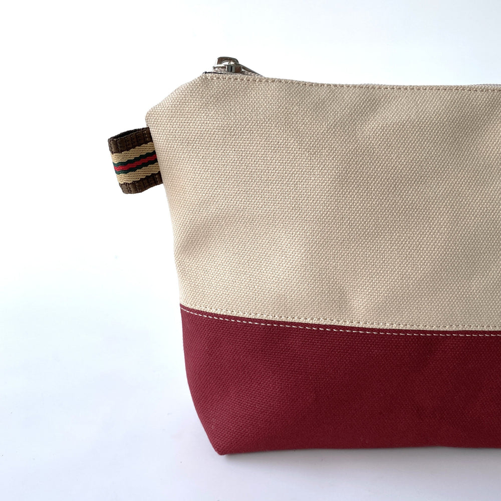 Close up of two tone beige and red pouch with white background.